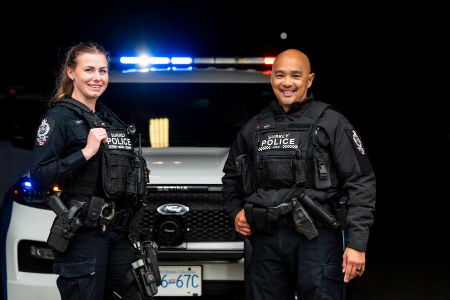Two police officers standing by a police car