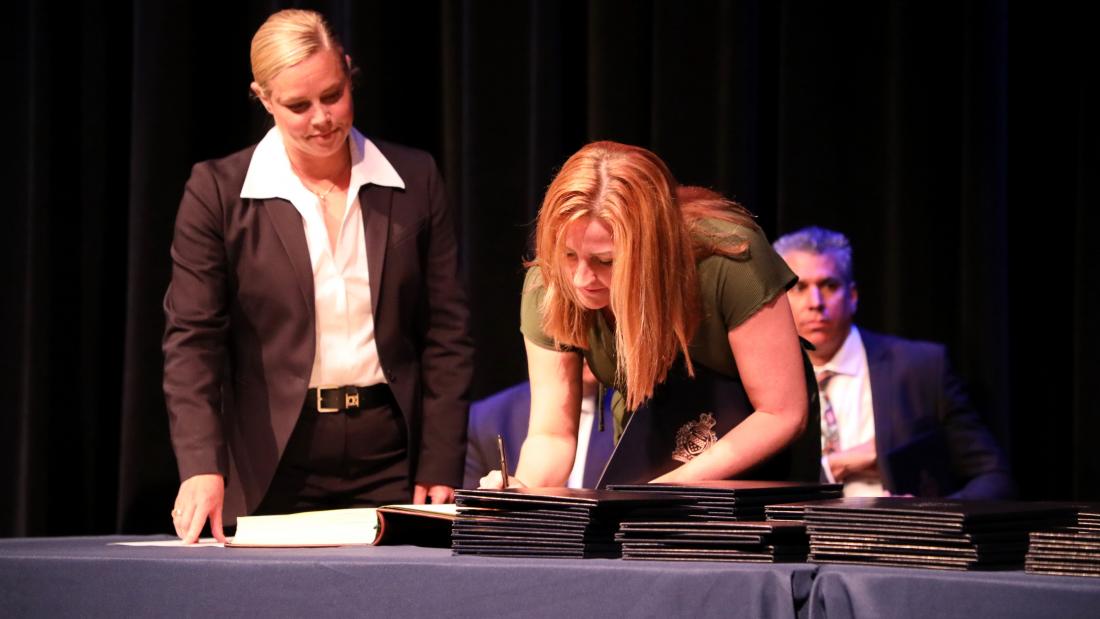 Deputy Chief Hyland stands alongside Administrative Assistant Melissa Booth as she signs the historical Leger